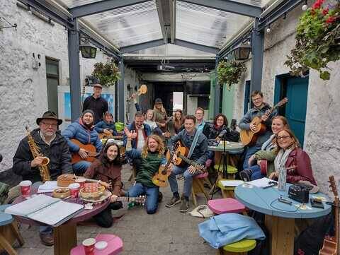 Galway Jam Circle musicians gathered together with guitars, ukuleles, and saxophone